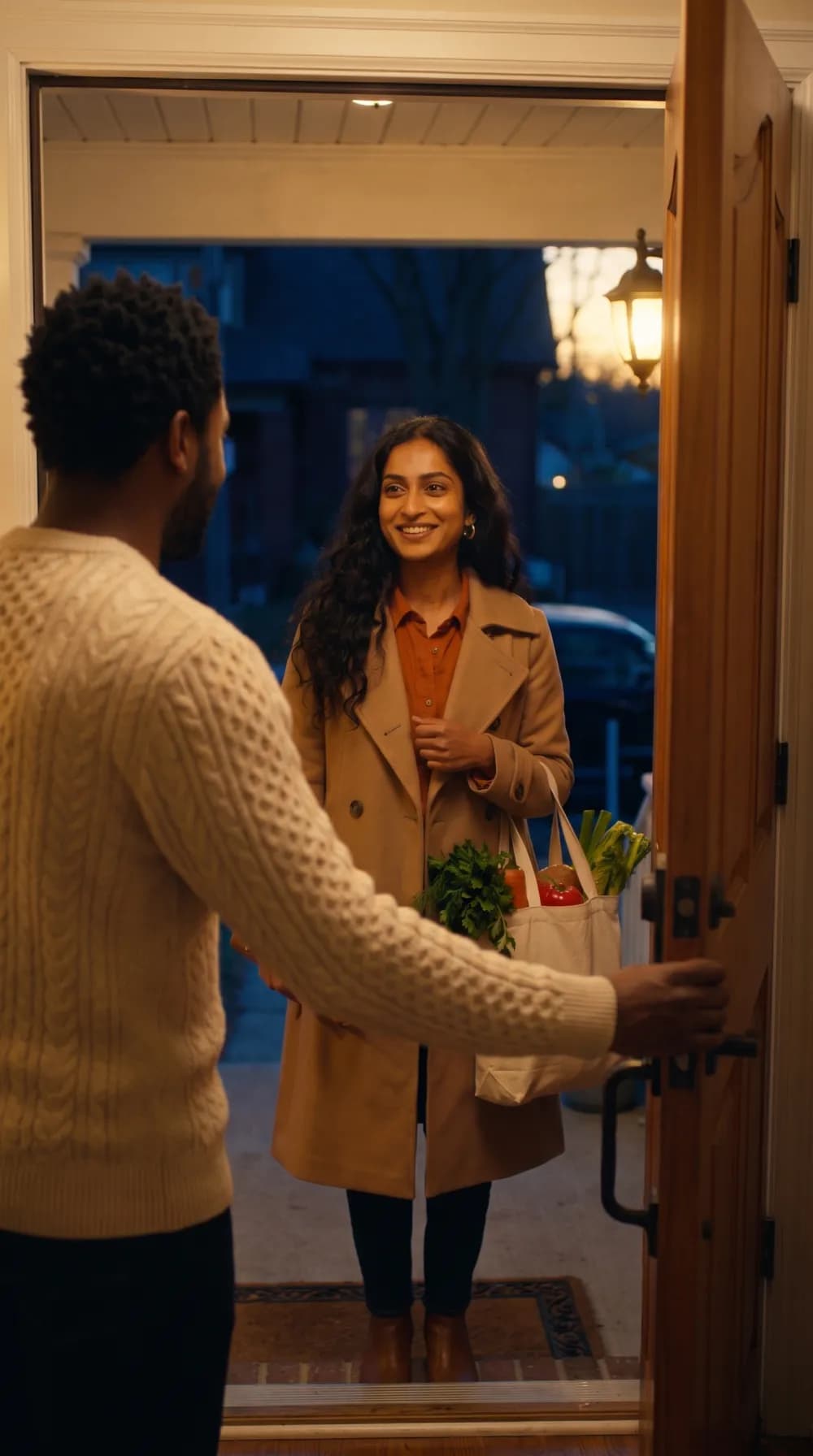 A host holds his front door open at dusk and a Tasker smiles on the step, groceries in hand
