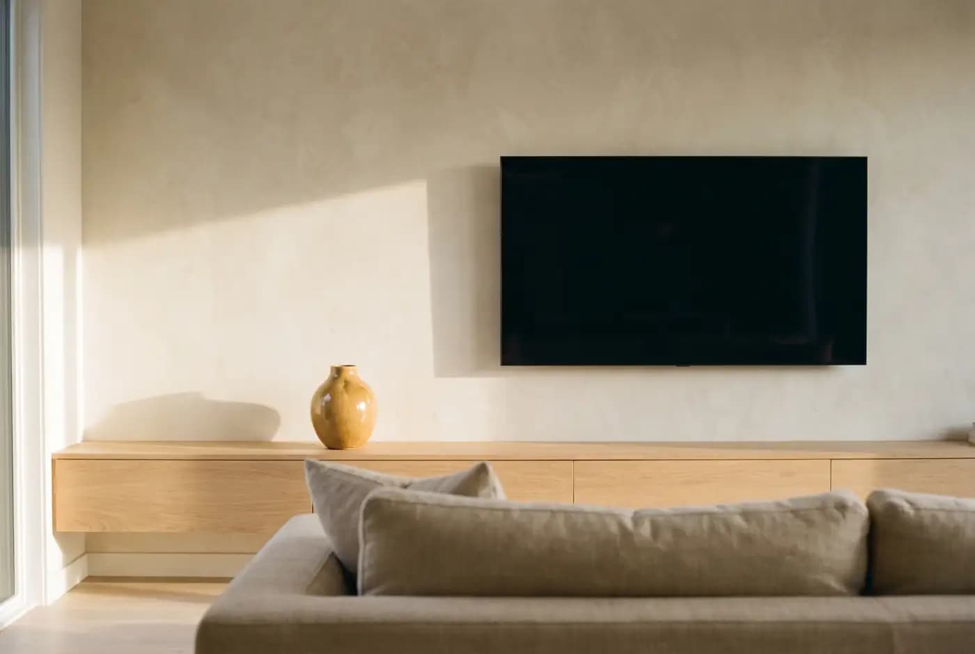 A finished living room with a television mounted flush to the wall and the cables hidden