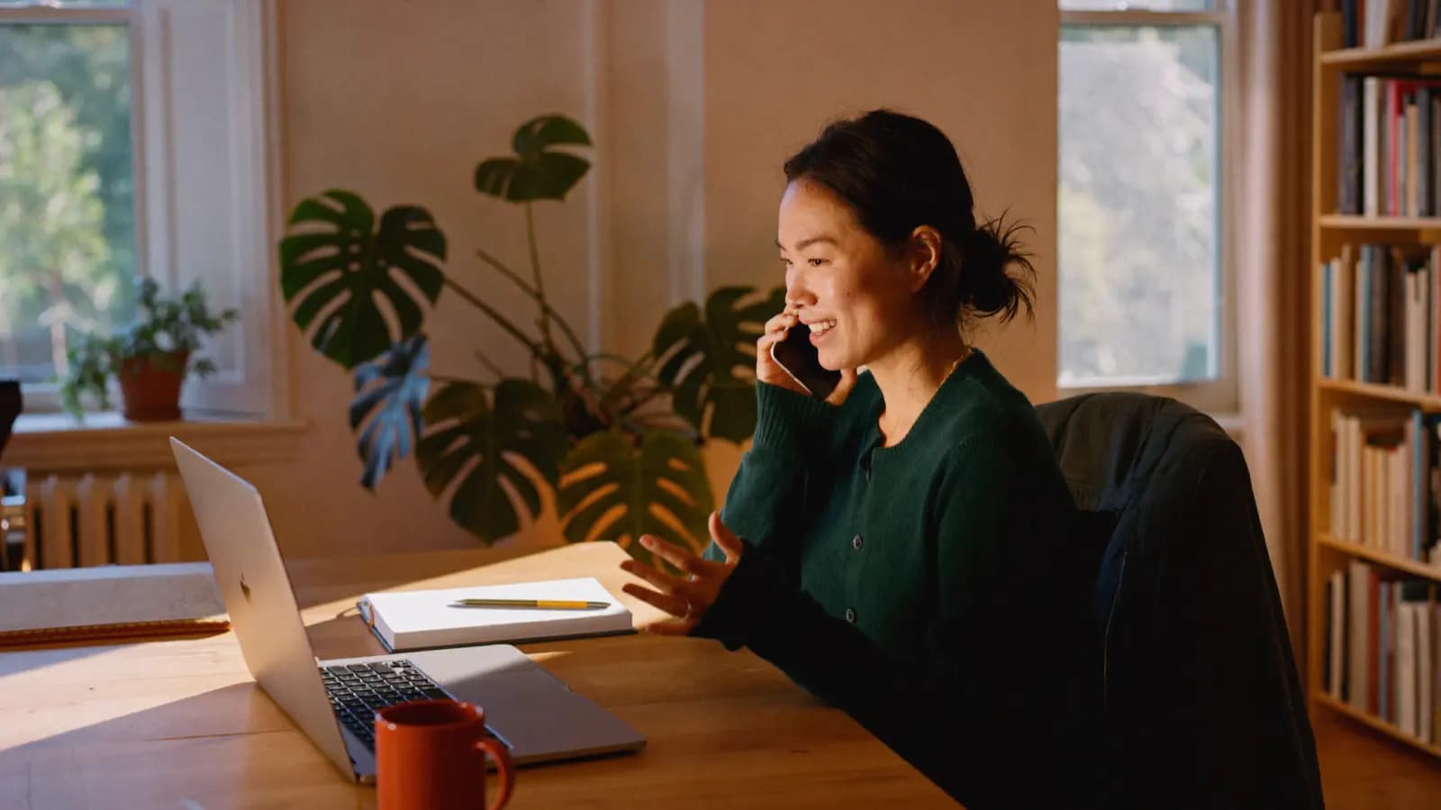 A freelancer working at a laptop at a plain table by a window.