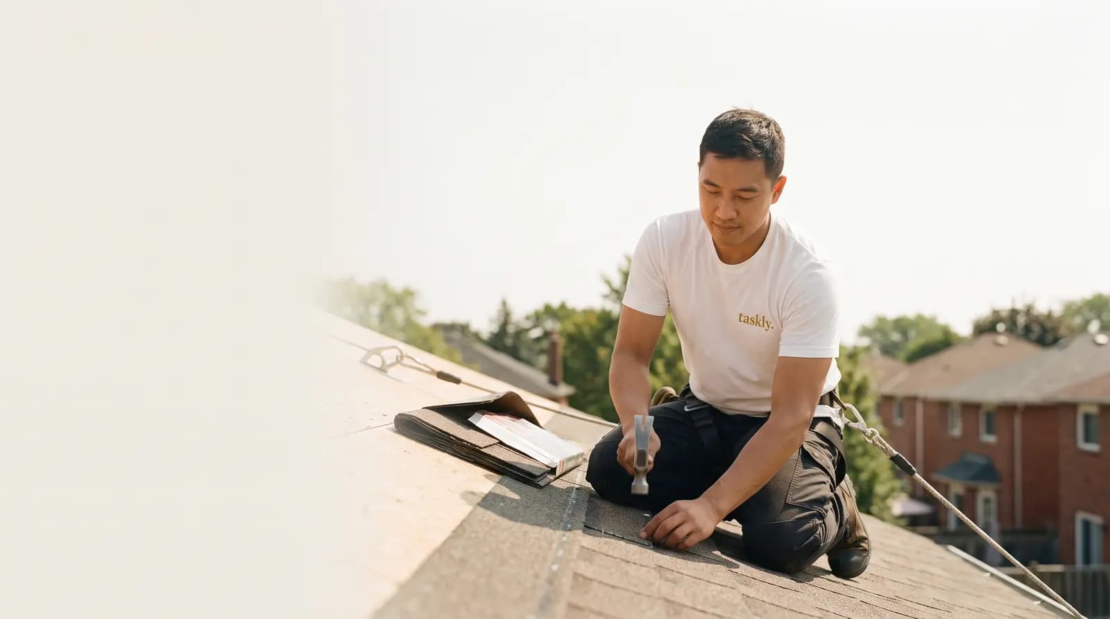 A course of asphalt shingles being nailed down on the pitched roof of a Toronto house.