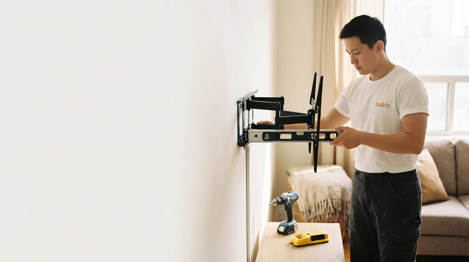 A TV bracket being levelled and mounted to a living room wall in Toronto.